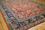 Angled view on the vintage carpet's red floral field and navy vine border.