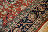 Angled view of the vintage carpet's navy vine border and madder red floral pile.