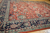 Corner detail showing the navy blue vine border beside the rust-red field with scrolling florals.