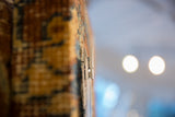 Clothespin on the textural edge of an antique Kerman rug fragment cork board.