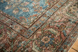 Worn pile of vintage Mahal carpet showing floral details, aqua blue, and red.