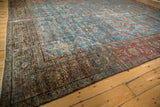 Vintage Mahal carpet border showing visible wear on cochineal red and aqua floral patterns.