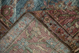 Folded vintage Mahal rug revealing hand-knotted foundation and worn aqua blue floral pile.
