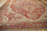 Low perspective across an antique Serapi rug showing serrated patterns in terracotta, ivory, and powder blue.