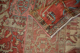 Rolled corner of an antique Serapi showing the terracotta field pattern and detailed Samovar border.