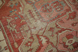 Visible hand-knotted structure and foundation of an antique Serapi carpet with time-softened terracotta tones.