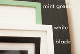 Slender handmade wall art frames with a flat profile in mint green, white, and black.