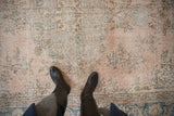 Distressed vintage Sparta rug showing faded dusty rose, teal vines, and foundation wear.