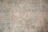 Faded dusty rose and teal arabesque on distressed vintage Sparta carpet with visible foundation.
