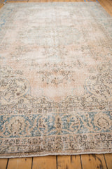 Distressed scrolling arabesque main border of vintage Sparta rug, with faded teal and wear.