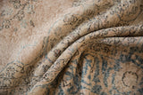 Textured folds of the distressed Sparta rug with faded teal and ivory patterns.