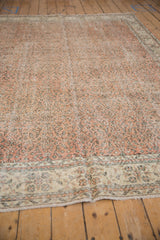Distressed vintage Sparta rug, pale terracotta field with scrolling charcoal vinery, textured wear.