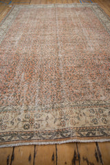 Distressed texture and fringed edge of a vintage Sparta carpet with delicate vinery.