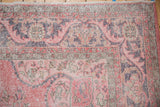 Corner of distressed Turkish Sparta rug, highlighting scrolling serrated leaves and floral vinery in pale pink.