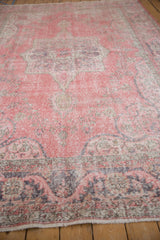 Distressed Sparta carpet border with faded pink and charcoal stylized dragon leaf motifs.