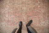 Close-up view of a distressed Turkish Isparta rug with dusty rose, brown, and pale green geometric vinery.