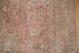 Distressed vintage Isparta rug detail: worn dusty rose field, pale coffee border, foundation visible.