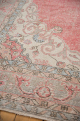 Distressed vintage Turkish Sparta carpet showing worn pale cochineal red and arabesque border.