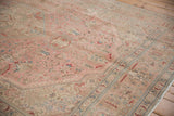 Distressed vintage Isparta carpet corner, showing faded dusty rose, beige, and aqua floral design.
