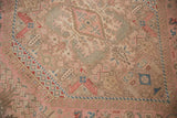 Distressed vintage Isparta rug detail with dusty rose, beige, and muted blue floral geometric patterns.