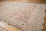 Distressed Isparta carpet corner showing faded floral motifs and soft beige, pink tones.