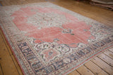 Distressed vintage Sparta rug corner showing ruby red abrashes and dark mauve arabesque border.