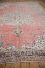 Textured distressed corner of a Sparta rug with muted dusty rose field and ornate border.