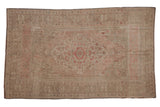 Distressed vintage Oushak rug, hand-knotted, featuring faded medallion in beige and dusty rose.
