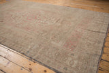 Worn beige, dusty rose, and muted green pile of a distressed Oushak carpet with visible foundation.