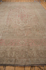 Distressed Oushak carpet's worn pile texture revealing dusty rose and sand patterns.
