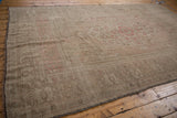 Close view of distressed texture and faded blush motifs on vintage Oushak rug.