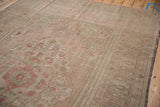 Distressed vintage Oushak rug showing even wear, muted beige, dusty pink geometric patterns, and intact selvage.