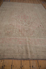 Distressed Oushak carpet edge with faded beige and dusty pink patterns, showing fringe.