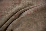 Folded distressed vintage Oushak rug's low pile, showing faint foundation.