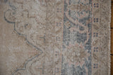 Distressed Sparta carpet pile with faded blue and pink ornate curvilinear patterns, side selvage.