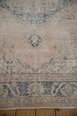 Distressed vintage Sparta carpet showing dusty denim blue scrolled tendrils on a cream field.