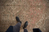 Distressed Persian Mehrivan carpet featuring faded pink, beige, and green geometric motifs.