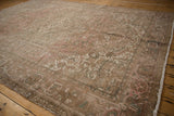 Distressed Mehrivan carpet corner showing geometric floral patterns, muted pinks, beige, and intact selvage.