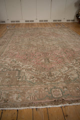 Worn texture of a vintage Mehrivan carpet with faded pink, beige, and green geometric motifs.
