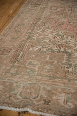 Distressed vintage Mehrivan carpet pile, revealing muted pink, beige, seafoam patterns and fringe.