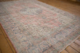 Distressed vintage Sparta rug, showing floral sprays and scrolling arabesque border in dusty blush, navy.