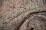 Textured surface of a distressed vintage Sparta carpet, showcasing faded blush, ivory, and blue patterns.