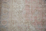 Faded floral palmettes and vinery on a distressed Turkish Sparta rug in blush, ivory, and soft mauve.