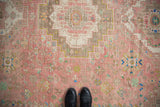 Distressed Abadeh carpet detail: worn blush and brown pile with playful floral and animal motifs.