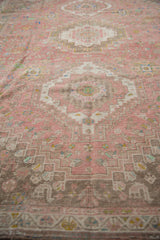 Distressed vintage Abadeh carpet shows visible wear, muted pink, brown, and ivory stepped patterns.