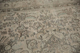 Distressed vintage Tabriz rug showcasing delicate floral vinery in soft ivory, charcoal, pale seafoam.