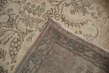 Distressed vintage Tabriz carpet corner, showing ivory pile wear revealing its hand-knotted foundation.