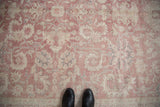 Distressed Sparta carpet field shows faded dusty rose and ivory scrolling floral patterns.