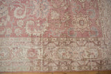 Distressed corner of vintage Turkish Sparta rug, pale rose field with floral vinery and borders.