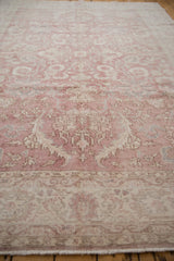 Distressed vintage Sparta carpet: faded dusty rose field, ivory floral vinery, and visible knot heads.